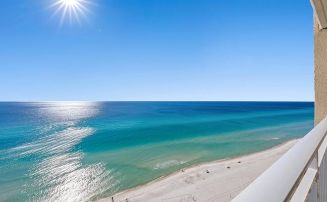 High-rise balcony view over white sand and turquoise Gulf water, Panama City Beach